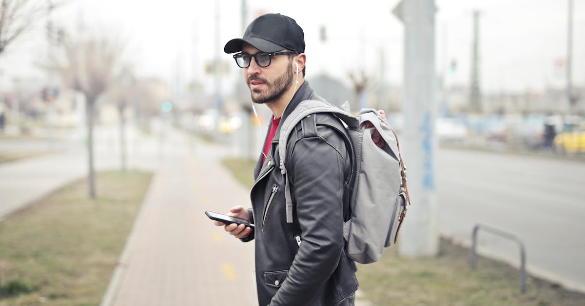 A fashionable young man in Budapest checking his smartphone on a busy street.